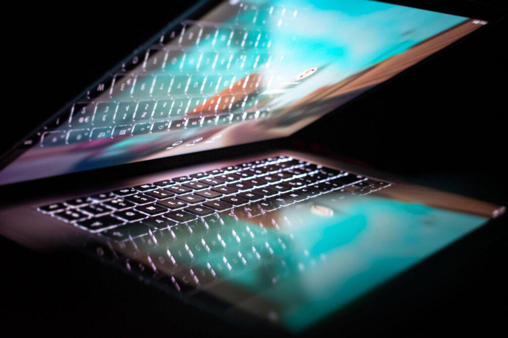 Photo d'un ordinateur portable ouvert au tiers. L'écran se reflète sur le côté clavier